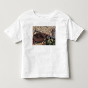 Een geweer, een militaire afdekking en een kantine kinder shirts