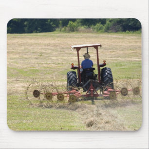 Een jonge jongen bestuurt een tractor die oogst muismat
