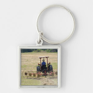 Een jonge jongen bestuurt een tractor die oogst sleutelhanger