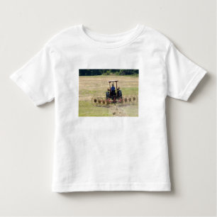 Een jonge jongen die een trekker bestuurt die oogs kinder shirts