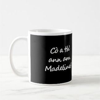 Eén kant van de mok zegt Cò a th' ann am Madeline?