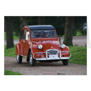 Een oude rode Citroen 2CV auto met een lachende vr