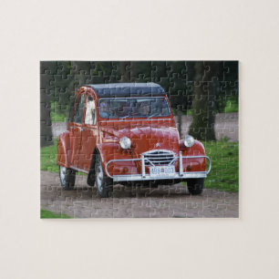 Een oude rode Citroen 2CV auto met een lachende vr Legpuzzel
