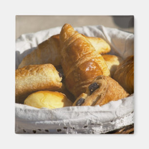 Een rieten ontbijtmand met croissants, en magneet