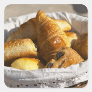 Een rieten ontbijtmand met croissants, en vierkante sticker