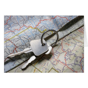 Een set autosleutels op een stapel wegenkaarten.