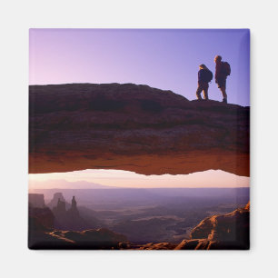 Een stel bekijkt zonsopgang vanaf Mesa Arch in Magneet