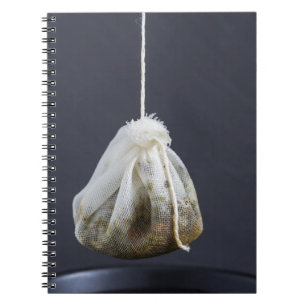 Een theezakje zit in een beker. notitieboek
