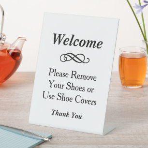Elegante witte welkom verwijder schoenen reclamebord met voetstuk