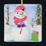 En Céramique Snowman avec foulard rose et ornement sucre de can<br><div class="desc">Snowman avec une écharpe rose et portant un sucre de canne. Paysage d'hiver et sac cadeau en vert citron avec un ours et la sucette à côté du bonhomme de neige. À l'arrière,  votre nom,  l'année et les jours de neige heureux peuvent être personnalisés. Aquarelle.</div>
