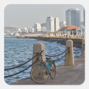 Fiets aan het water met stadsbeeld van Yantai Vierkante Sticker