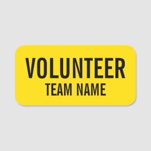 Gele vrijwilliger-badge met de naam van het team naamplaatje