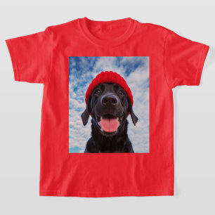 Gelukkige Labrador in een rode muts onder een blau T-shirt