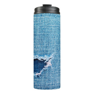 Gevulde denimachtergrond. Kantelgat in de stof Thermosbeker