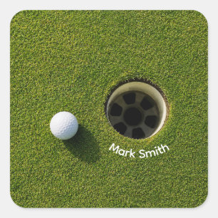 Golfbal naast hole op groene gras golfbaan vierkante sticker