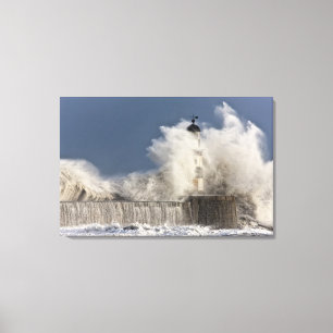 Golven kruipen tegen een vuurtoren canvas afdruk