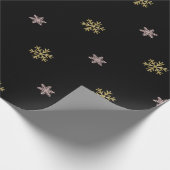 Goudglitter en roze sneeuwvlokken op zwarte kerst cadeaupapier (Hoek)