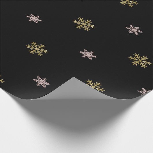 Goudglitter en roze sneeuwvlokken op zwarte kerst cadeaupapier (Hoek)