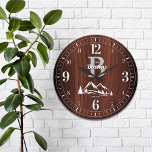 Grande Horloge Ronde Mountain Home Nom de famille<br><div class="desc">Amusant,  nom de famille personnalisé et design monogramme. Fait le cadeau parfait pour un ménage,  mariage,  ou toute occasion! Des pics enneigés et des pins hivernaux sur un panneau en faux bois d'érable profond et riche.</div>