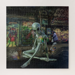 GREEN GREY ALIEN SITTING ON BETALING WITH GRAFFITI LEGPUZZEL