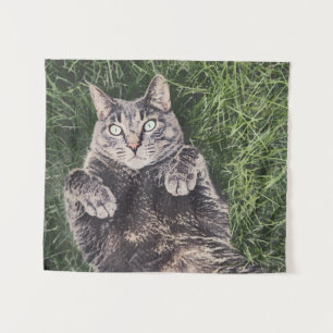 grijze kat die in het gras ligt wandkleed