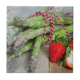 Groene asperges met aardbeien op hout tegeltje