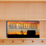 Home Sweet Home Sunset Silhouette<br><div class="desc">Panneau de boîte en bois peint en noir conçu pour être suspendu ou debout et qui présente l'image d'un ciel de coucher de soleil coloré et la silhouette noire d'une maison avec les mots "HOME SWEET HOME" imprimés en grandes lettres noires. Un doux ajout à n'importe quelle maison !</div>