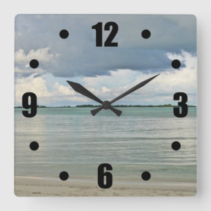 HORLOGE CARRÉE LE SOLEIL PASSE PAR DES NUAGES SOMBRES À LA PLAGE