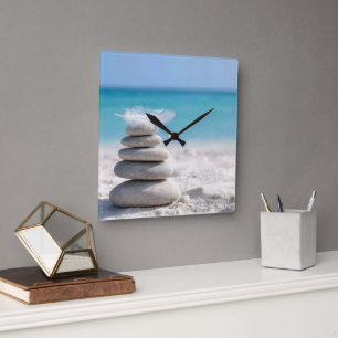 Horloge Carrée Plume blanc sur un cairn de plage