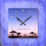 Horloge Carrée Sur La Plage California Purple Pink Sunset Photo<br><div class="desc">"A l'heure de la plage." Un coucher de soleil violet bleu et rose sur une plage de Californie du Sud aux palapas en chaume respire la détente et la réflexion. Détendez-vous, sentez l'air de l'océan et rappelez-vous les souvenirs de l'été chaque fois que vous regardez l'heure sur cette horloge murale...</div>