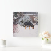 Horloge Carrée Winter snow scene with cute black and tan dog (Maison)