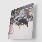Horloge Carrée Winter snow scene with cute black and tan dog (Angle)