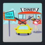 Horloge murale des années 1950<br><div class="desc">Servez quelque chose de spécial avec cette horloge murale des années 50. Le dessin animé est composé d'un bâtiment en brique rouge avec des fenêtres bleues, de portes doubles grises et d'un panneau blanc qui dit "Diner" perché sur le toit. Dans le parking, un deuxième panneau est sur un poteau....</div>