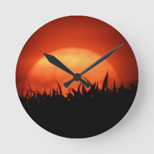 Horloge Ronde Coucher de soleil rouge derrière l'herbe noire