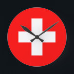 Horloge Ronde drapeau suisse<br><div class="desc">Le drapeau de la Suisse (allemand : Schweizerfahne ; français : drapeau de la Suisse ; italien : bandiera svizzera ; romanche : bandiera de la Svizra) affiche une croix blanche au centre d'un champ rouge carré. La croix blanche est connue sous le nom de croix suisse.</div>