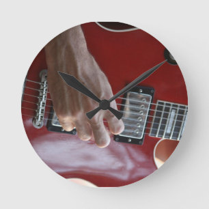 Horloge Ronde Main jouant la guitare électrique rouge près de 
