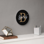 Horloge Ronde Monogramme moderne élégant Nom Black Gold Script<br><div class="desc">L'horloge Monogram Name Black Gold Script Clock est un garde-temps élégant et personnalisé, parfait pour n'importe quelle maison ou bureau. Cette horloge comporte un visage noir élégant avec élégant script or, vous permettant de le customiser avec votre monogramme et votre nom. Le design moderne et les couleurs chics en font...</div>