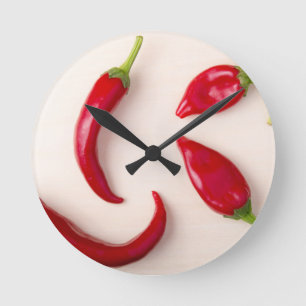 Horloge Ronde Poivrons de piment rouge chauds sur un conseil en
