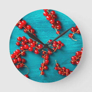 Horloge Ronde Red currant on blue background. Colorful food desi