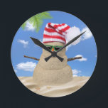 Horloge Ronde Tropical Christmas Sand Snowman<br><div class="desc">Sable de Noël tropical bonhomme de neige avec casquette rayé rouge et blanc et lunettes de soleil vert sur le sable.</div>