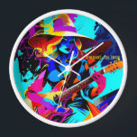 Horloge Sorcière guitariste pop-art colorée<br><div class="desc">L'image présente une sorcière jouant une guitare électrique, dépeinte dans un style artistique vibrant et coloré. La sorcière porte un grand casquette à large bord et a des cheveux flottants et ondulés dans les tons jaune et bleu. Son expression est focalisée et intense alors qu'elle brille la guitare, qui se...</div>