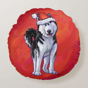 Husky met kerstmuts op rood rond kussen