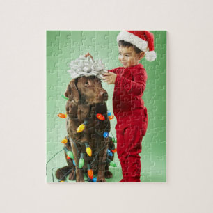 Jonge jongen die kerstverlichting rond een hond wi legpuzzel