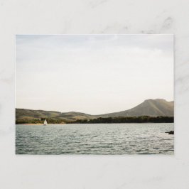 Klein schip dat 's middags op een meer vaart briefkaart