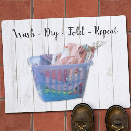 Kleurrijk gevouwen wasgoed op hanen in een blauwe  deurmat