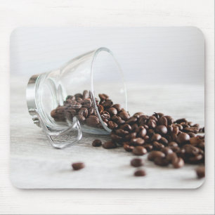 Koffiebonen die uit een duidelijke Koffiebeker lop Muismat