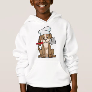 Le chien cuisinier avec le casquette et la spatule
