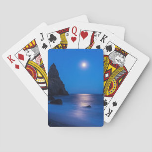 Maanopkomst weerspiegeld op oceaan en zee stapels pokerkaarten