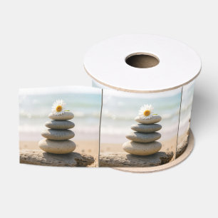 Madeliefje op een stenen strandcairn met drijfhout grosgrain lint