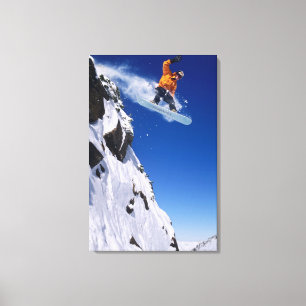 Man op een snowboard springend van een richel bij canvas afdruk